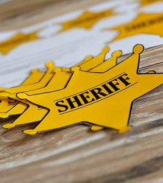 there is a sign that says sheriff on the side of a wooden table with other signs behind it