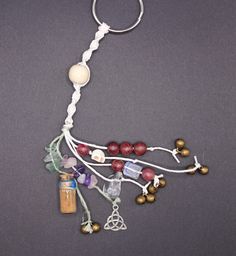 a necklace with beads and charms hanging from it's side on a gray surface