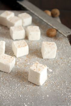 several cubes of marshmallow sitting on top of a cutting board next to a knife