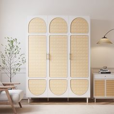 a white cabinet sitting in the middle of a living room next to a table and chair