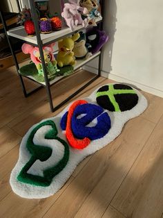 there is a pile of stuffed animals on the floor in front of a shelf with toys