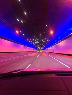 the inside of a car driving through a tunnel with lights on and purple lighting in the ceiling