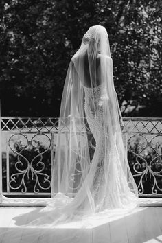 the back of a bride's dress as she stands in front of a fence