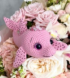 a pink crocheted stuffed animal surrounded by white and pink flowers in a bouquet