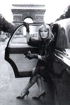 a woman sitting in the driver's seat of a car with her hand on the door handle