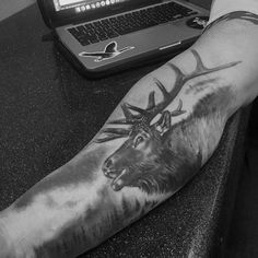 a man with a deer tattoo on his arm next to a laptop