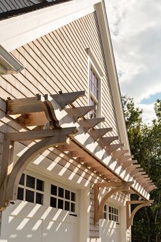 a wooden pergolan attached to the side of a house next to a garage