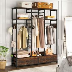 an open closet with clothes hanging on the shelves and shoes sitting on top of it