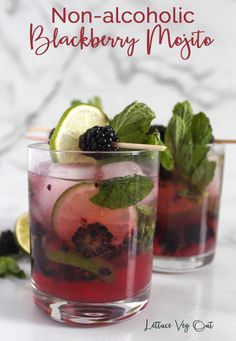 two glasses filled with blackberry mojita on top of a table