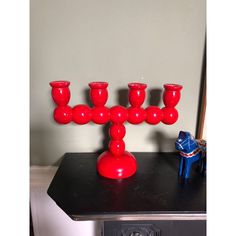 a red candle holder sitting on top of a black table next to a blue horse