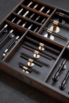 an assortment of different types of tools in a wooden box on a table with black background