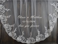 the wedding veil has been embroidered on it and is hanging in front of a wooden door