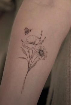 a tattoo with flowers and a butterfly on the side of her arm, which is black and white