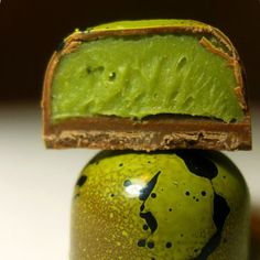 a green vase sitting on top of a white table next to a piece of wood