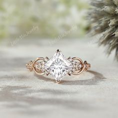 an engagement ring with a princess's cut diamond surrounded by small white diamonds on top