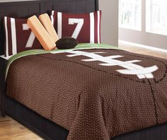 a bed with brown and white comforters, pillows and baseball bats on top of it