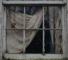 an old window with curtains in it