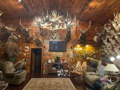 a living room filled with lots of deer heads mounted on the wall above it's fireplace