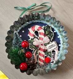 a christmas decoration with candy canes, pine cones and holly berries on a plate