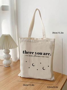 a tote bag sitting on top of a wooden table next to a lamp and vase