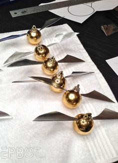 several golden objects are lined up on top of white paper with scissors and other items in the background