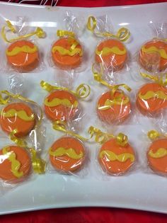 some orange and yellow decorated cupcakes in plastic wrappers on a white plate