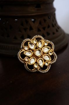 Exquisitely detailed kundan ring with kundan encrusted in a floral pattern and daintedly lined with shell pearls. This oversized cocktail ring is all you need to accentuate your look. Ring - Adjustable Style Tip - Style this with Classic banarasi sarees, lehengas or indo western wear dresses. A perfect match with almost any traditional classic. A very chic and contemporary ring that is a favourite for all ages. Handcrafted in Jammu and Kashmir Paisley Pop travels the depths of India to learn tec Traditional Kundan Rings For Festive Occasions, Kundan Temple Jewelry Ring For Festive Occasions, Festive Kundan Temple Jewelry Ring, Festive Kundan Rings With Stone Setting, Festive Gold Kundan Ring, Kundan Meenakari Toe Ring, Meenakari Kundan Toe Ring, Festive Kundan Rings With Stone Work, Festive Kundan Meenakari Rings