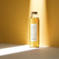 a bottle of liquid sitting on top of a white table next to a yellow wall