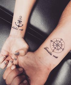 two people holding hands with tattoos on their arms and one has a compass tattoo on the wrist