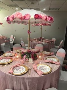 a table set up with pink and gold plates, napkins, and an umbrella