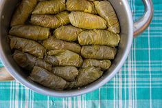 a pot filled with stuffed grape leaves on top of a blue and white checkered table cloth