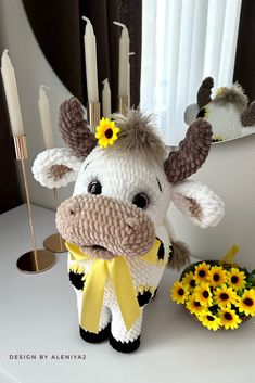 a stuffed cow with a yellow ribbon around it's neck sitting on a table