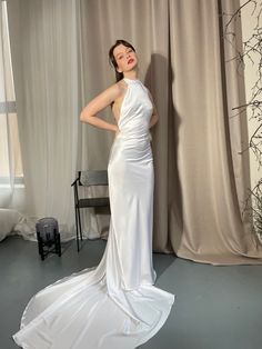 a woman standing in front of a curtain wearing a white dress and posing for the camera