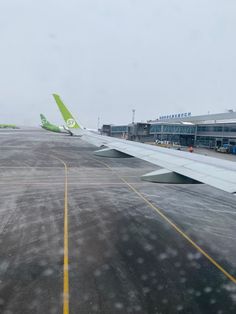 an airplane is parked on the tarmac at an airport with snow falling from the sky