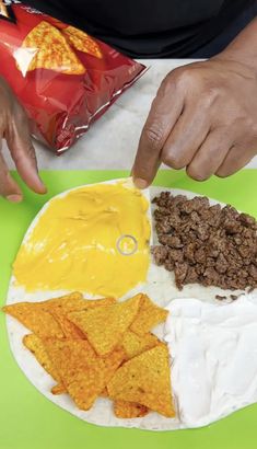 a person making chips and dips on a paper plate