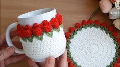 two crocheted coffee mug cozyies are being held by someone's hand