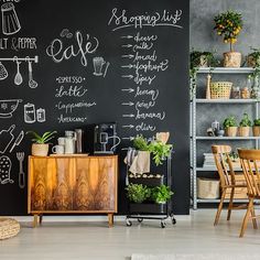 a chalkboard wall in the corner of a room with wooden furniture and potted plants