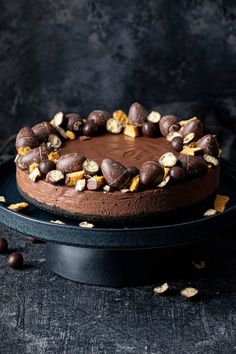 a cake with chocolate frosting and nuts in the shape of a heart on a black plate