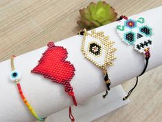 four different bracelets on a napkin with a flower in the background and a succulent plant next to it