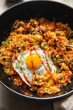 an egg is on top of rice in a skillet