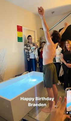 a man standing in front of a bath tub with his arms up and hands raised