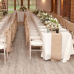 the tables are set up with white linens and flower centerpieces on them