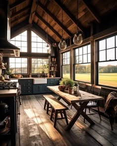 a rustic kitchen with wooden floors and large windows overlooking the field outside at sunset or dawn