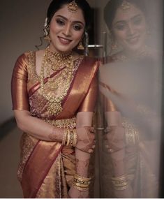 a woman in a gold and red sari standing next to another woman with her arms crossed