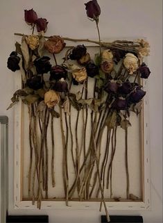 dried flowers are arranged in an old frame