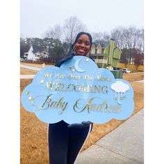 a woman holding up a welcome sign for her baby