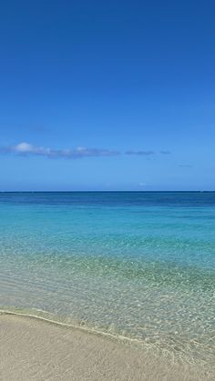 an empty beach with clear blue water on a sunny day