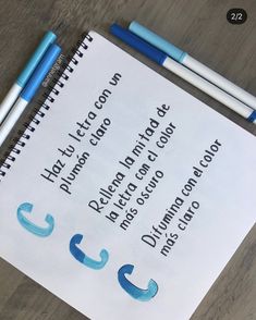 two blue and white pencils sitting on top of a piece of paper next to some writing