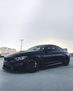 a black car parked in a parking lot next to a building with no people on it