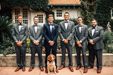 a group of men standing next to each other with a dog in front of them